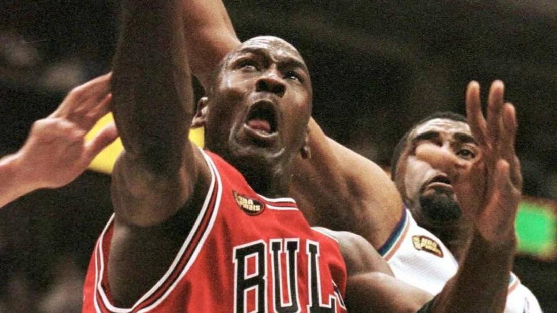 Michael Jordan, seen here with Phil Jackson, raises his NBA Finals MVP trophy following a last-second shot to secure a third straight title for the Chicago Bulls.