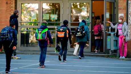 Children respect social distance rules when they enter Petri elementary school in Dortmund, western Germany, on Thursday, when the school reopens for a number of students.