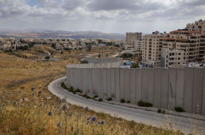 In this Friday, June 19, 2020 photo, A view of Shuafat refugee camp is seen behind section of Israel's separation barrier in Jerusalem, Friday, June 19, 2020. (AP Photo/Oded Balilty)