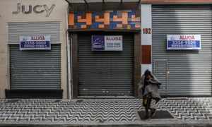 A homeless man walks in front of a shuttered shop with a ‘For Lease’ sign in downtown amidst the coronavirus pandemic on 29 June 2020 in Sao Paulo, Brazil.