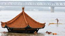 Residents swim past a riverside pavilion submerged by the flooded Yangtze River in Wuhan in central China&#39;s Hubei province on July 8.