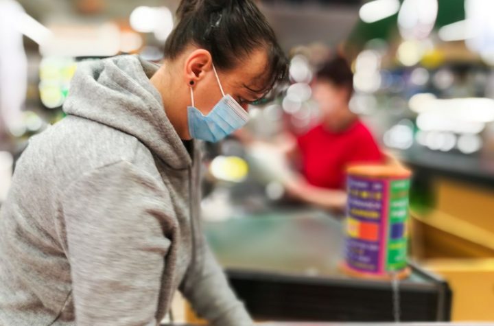 Woman wearing protective face mask and gloves at checkout