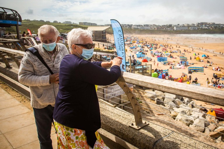 An elderly couple wearing masks at the Fistral beach in Newquay, Cornwall. 31st July 2020
