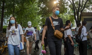 People wearing face masks to protect against the coronavirus walk along a street in Beijing, Friday, 31 July 2020.
