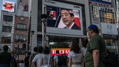 People watch Abe&#39;s press conference in Tokyo on Friday. 