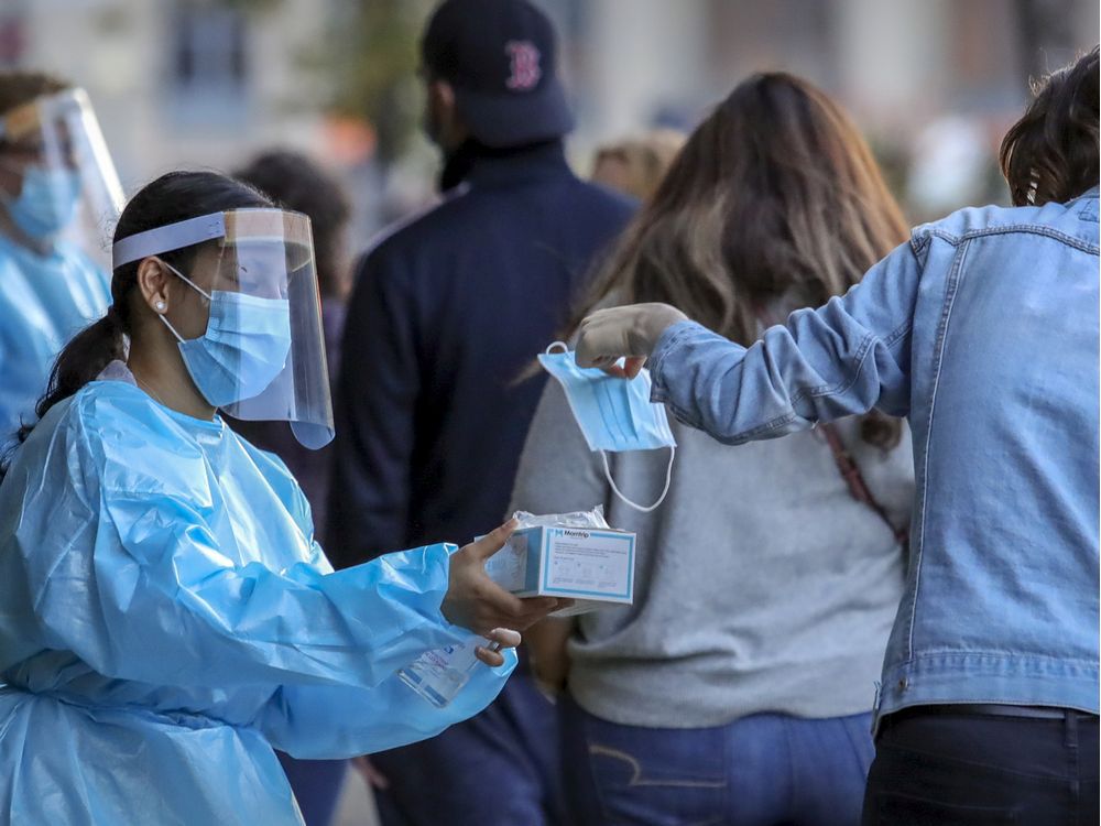 MONTREAL, QUE.: SEPTEMBER 24, 2020 -- Staff from Park Extension Covid-19 testing centre hands surgical mask to a woman waiting in line in Montreal Thursday September 24, 2020. (John Mahoney / MONTREAL GAZETTE) ORG XMIT: 65056 - 4406