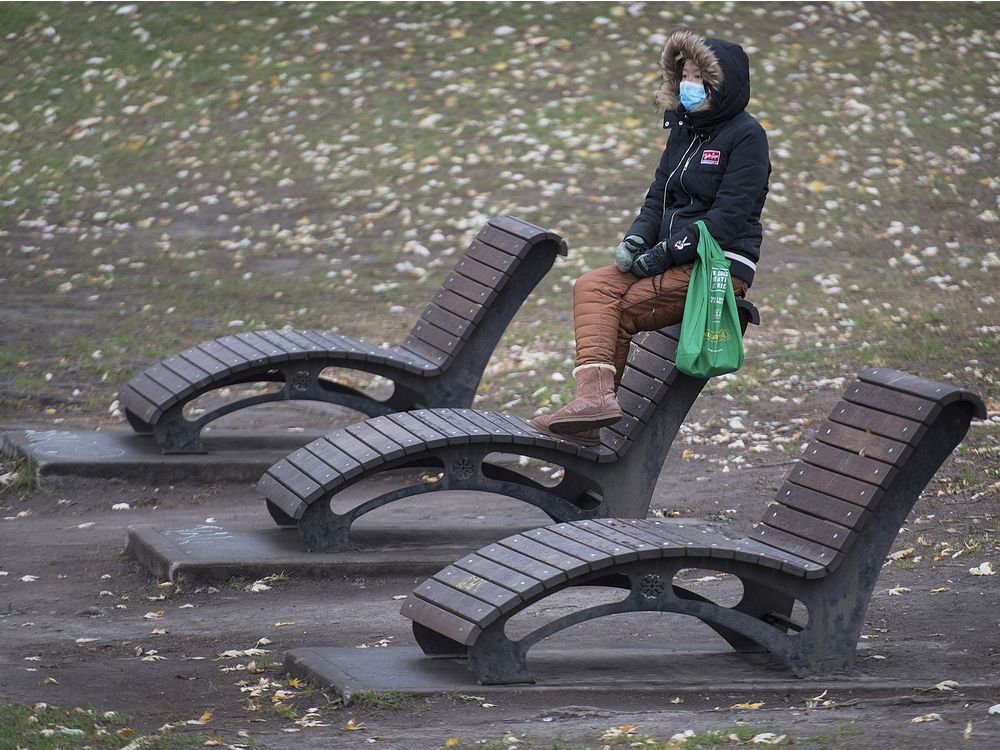 CP-Web. A woman wears a face mask as she sits in a park in Montreal, Sunday, November 15, 2020. THE CANADIAN PRESS/Graham Hughes ORG XMIT: GMH114