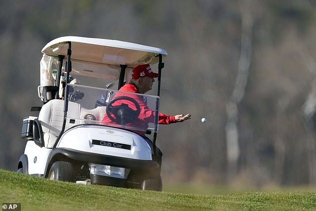 President Trump throws a golf ball from his cart while playing golf at his club in Virginia