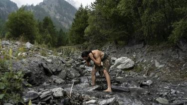 A man dressed as a Neanderthal man washes in a river in the Italian Alps [MARCO BERTORELLO / AFP/Archives]