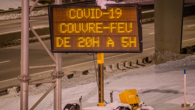 Affiche au bord de l'autoroute qui indique les heures du couvre-feu québécois.