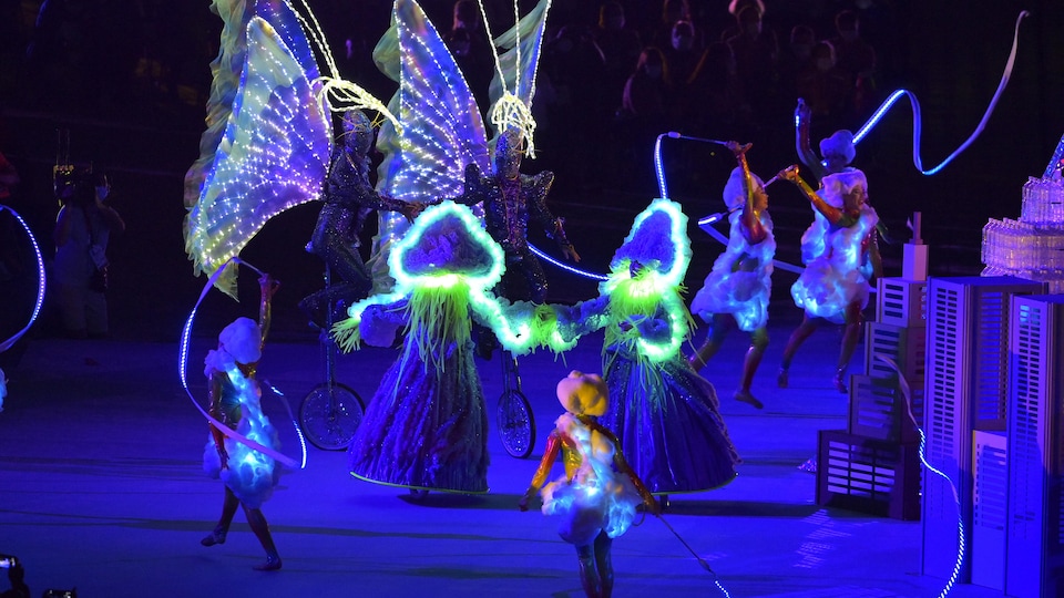 Artists dance and perform a routine with bright costumes. 