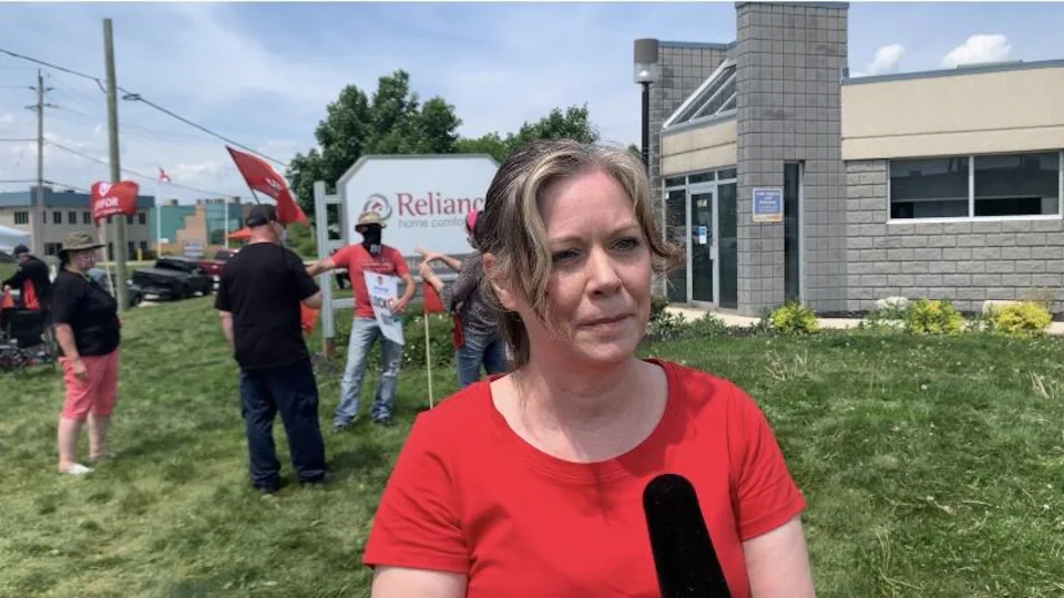 A woman reporter with a red sweater answers questions