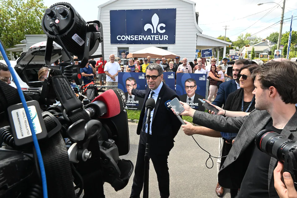 Eric Duhaime is in a press scrum in front of his campaign office.  There are also tens of activists.