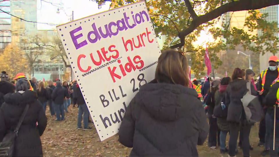 A protester holds a sign accusing the government of cutting education.