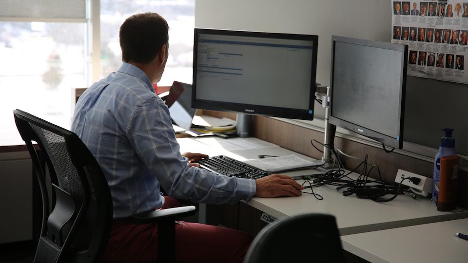 A man from behind is sitting in front of a computer.
