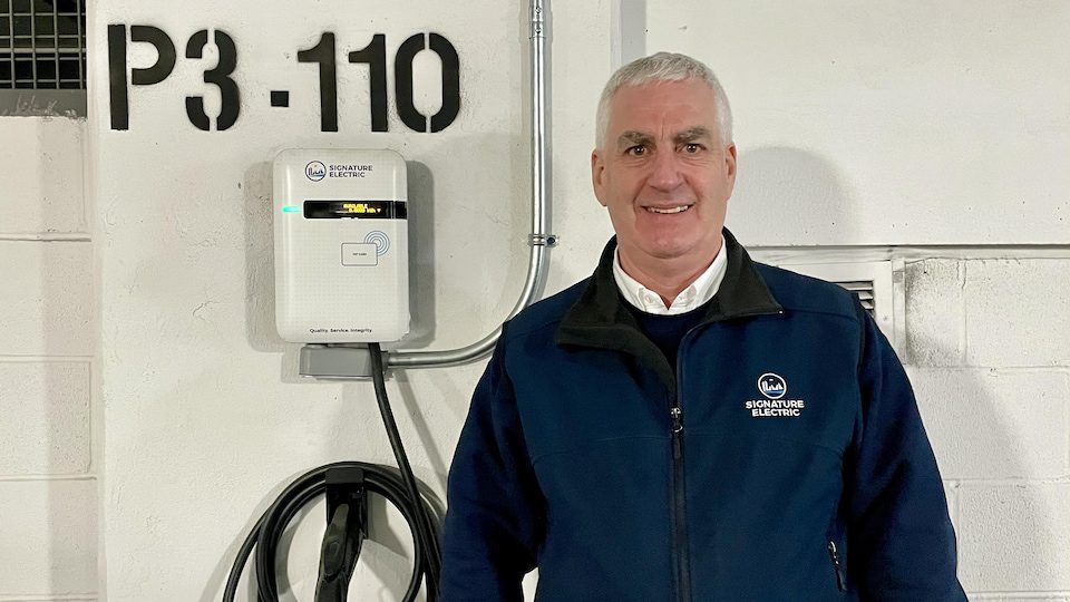 A smiling man next to a charging station.