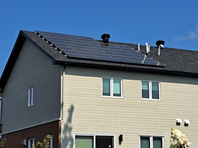 Jose Legris is behind his Net Zero house in Mascouche, where you can see the solar panels on the roof.