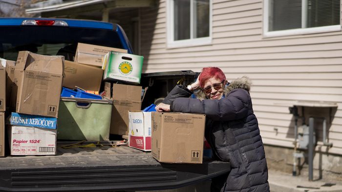 A woman leans on a box placed in the back of a van.