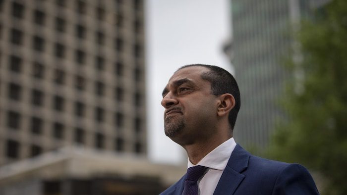 Portrait of a minister in front of a building, outdoors. 