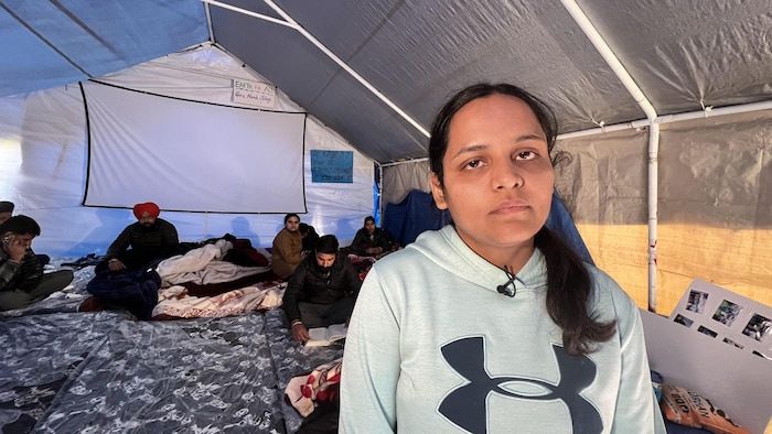 Simrat Kaur in a tent at Brampton Camp. Other temporary workers sat on mattresses behind her.