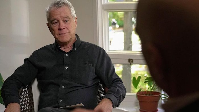 A man is sitting in front of a window.